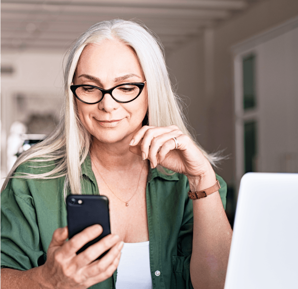 Woman with white hair looking down at her smartphone