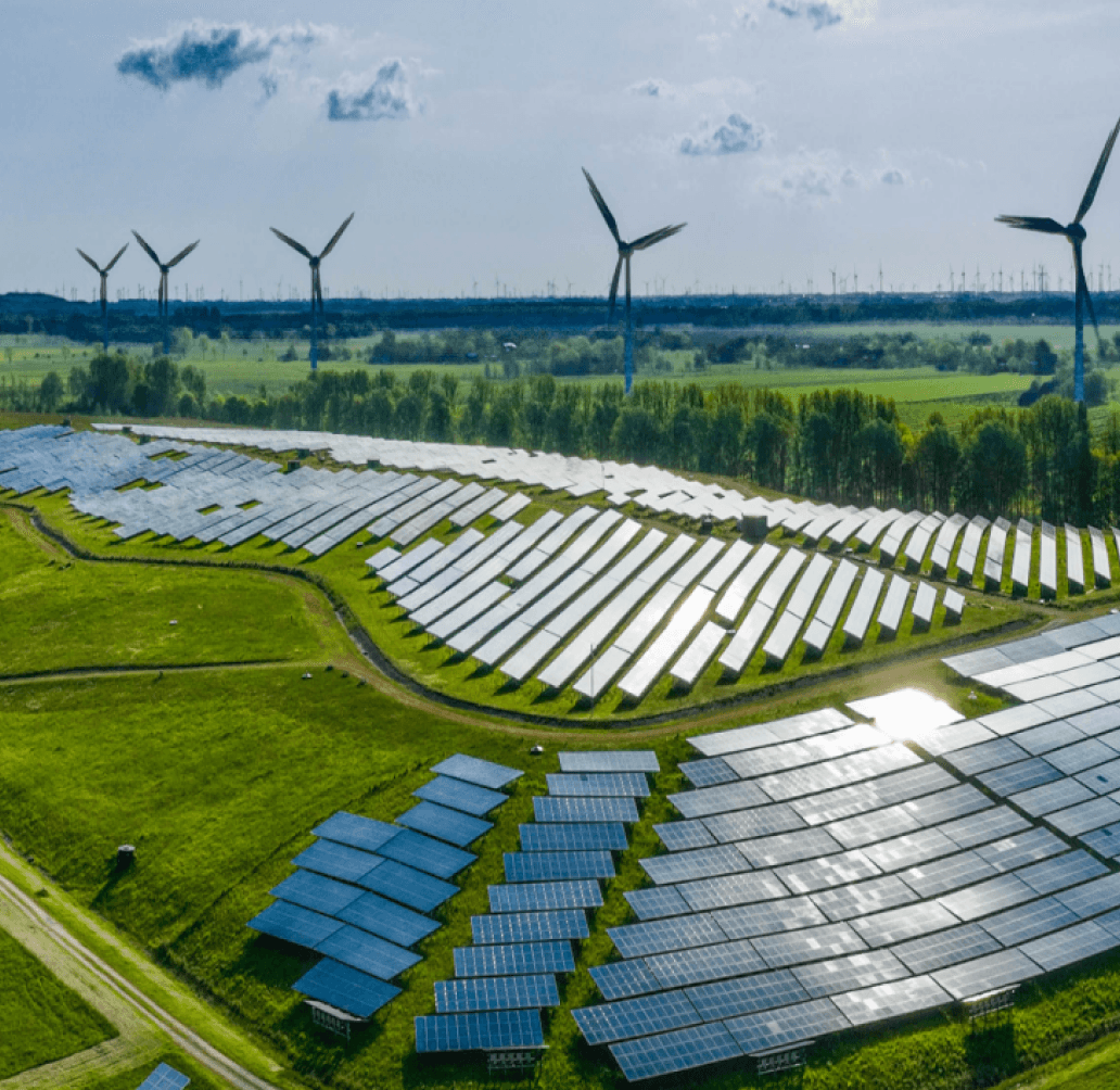 A high point of view of sunny day showing a grassy field with solar panels and windmills.